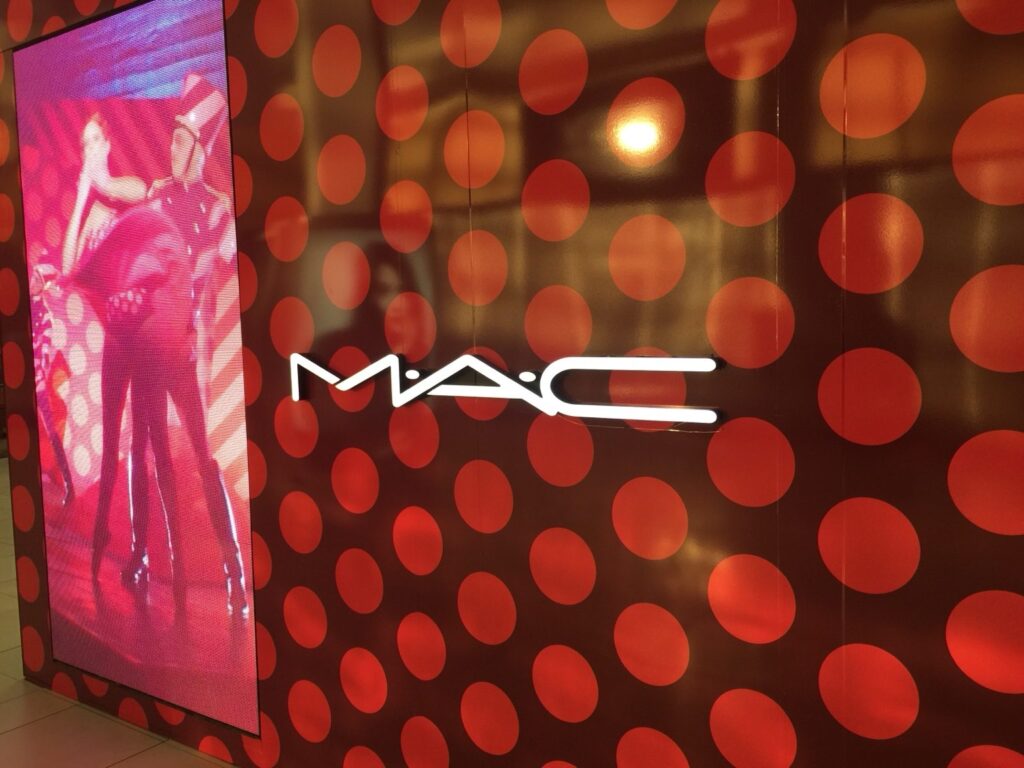 MAC Cosmetics illuminated logo on burgundy and red circular-pattern retail wall wrap at The Florida Mall in Orlando