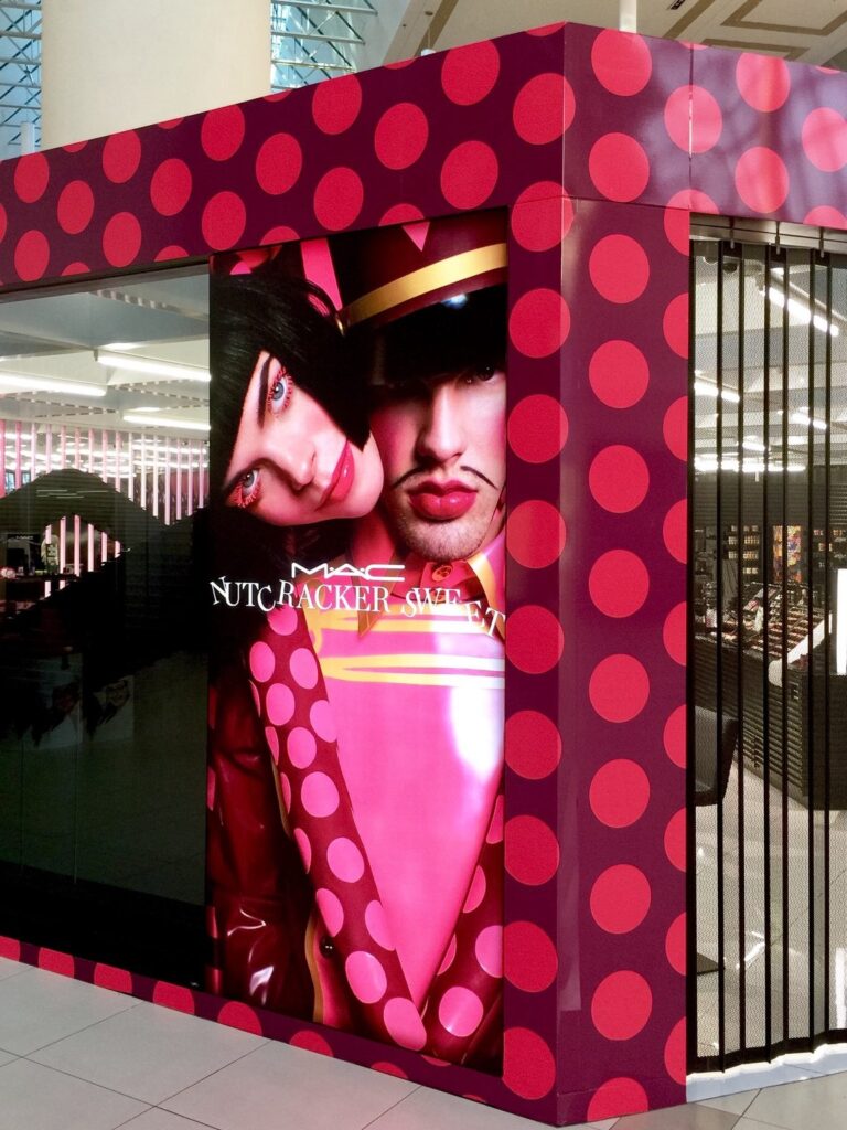 MAC Nutcracker Sweet promotional graphics installed alongside red patterned storefront wall at The Florida Mall Orlando