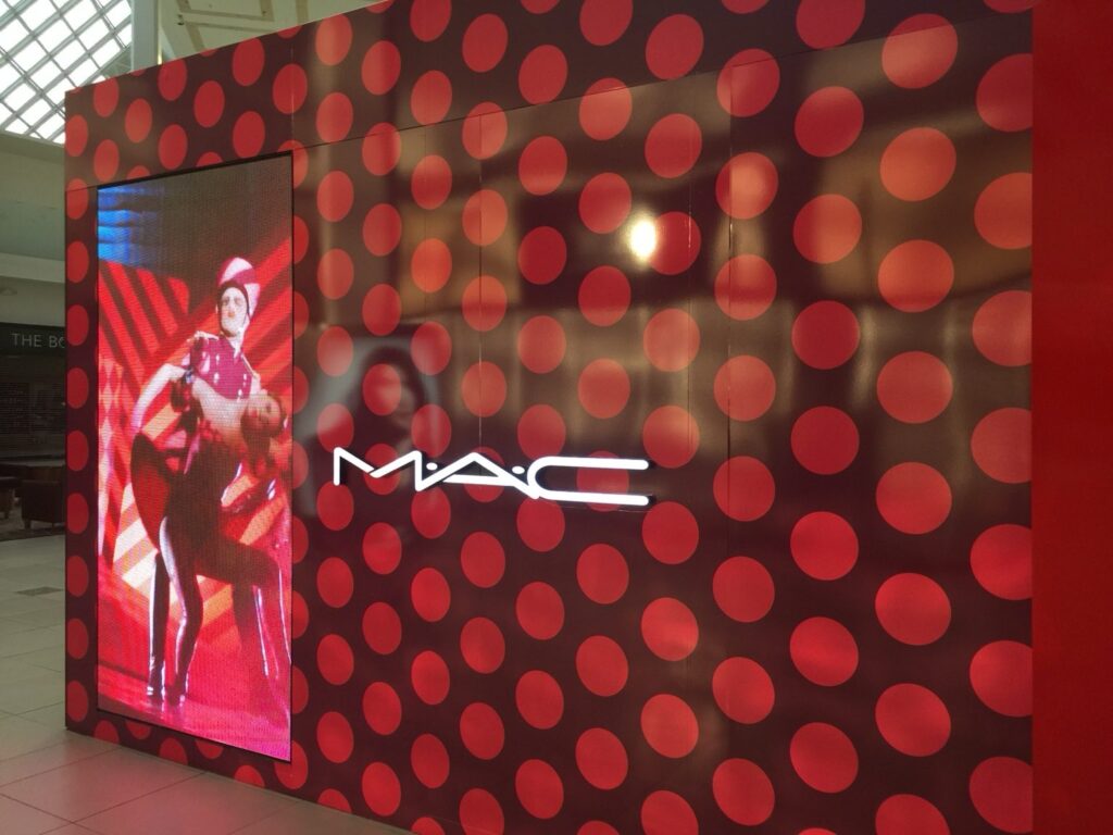Full MAC Cosmetics retail wall wrap featuring red circular pattern and tall promotional digital display in an Orlando mall