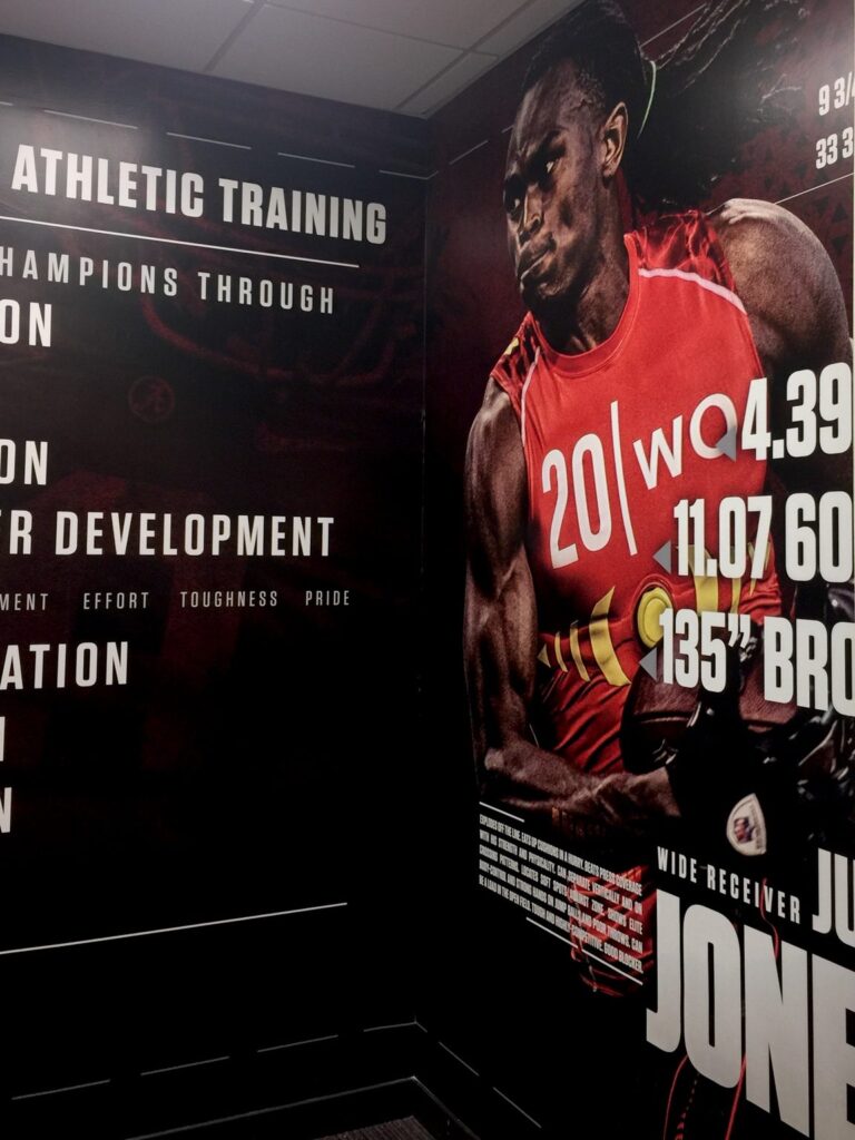 University of Alabama athletic training room corner with floor-to-ceiling Julio Jones football graphic and athletic development wall text