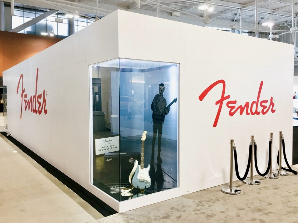 Fender exhibition booth at Music City Center with red logo graphics and a lit guitar display window.