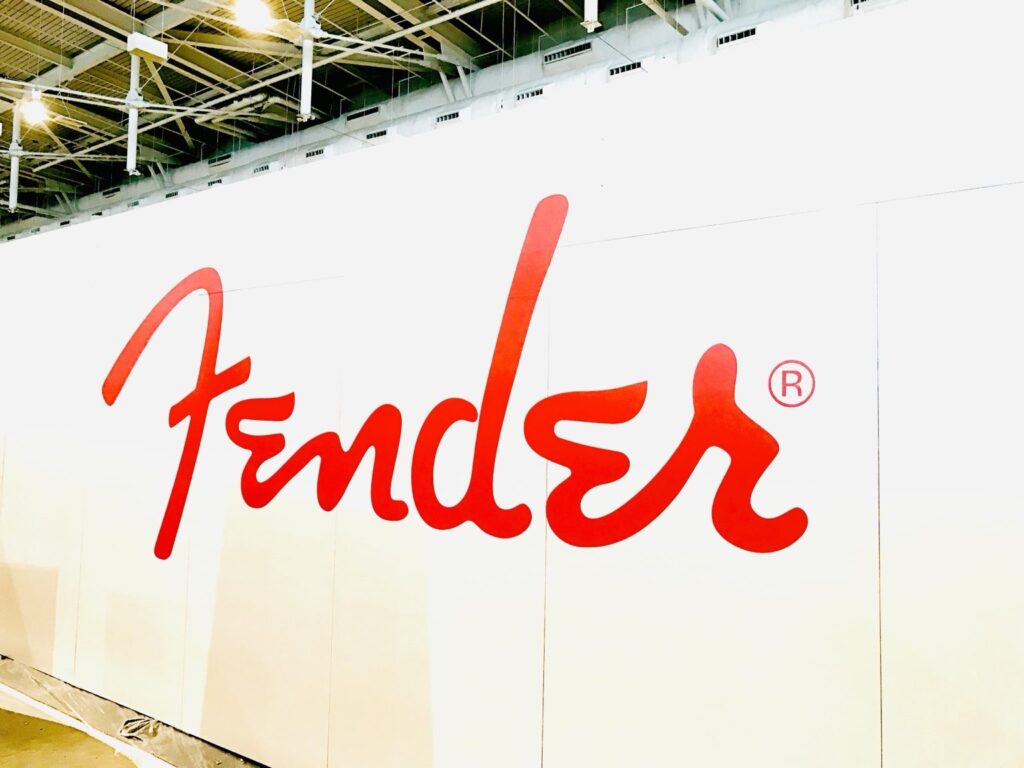 Oversized red Fender script logo wall graphic on a white booth wall, part of the Nashville trade show graphics.