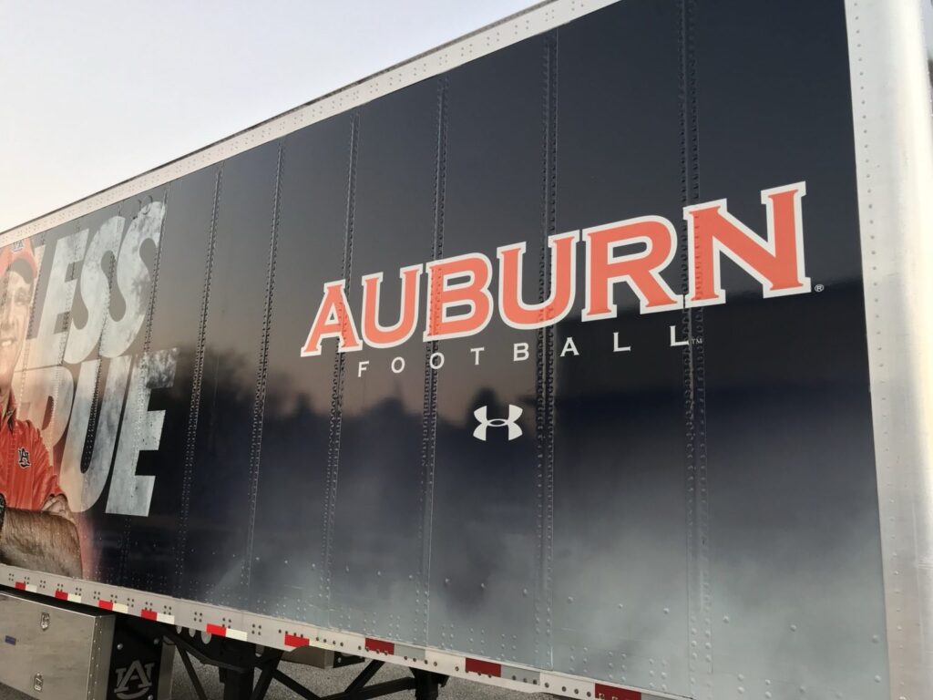 Close view of Auburn Football orange lettering and Under Armour logo on navy blue trailer wrap graphics