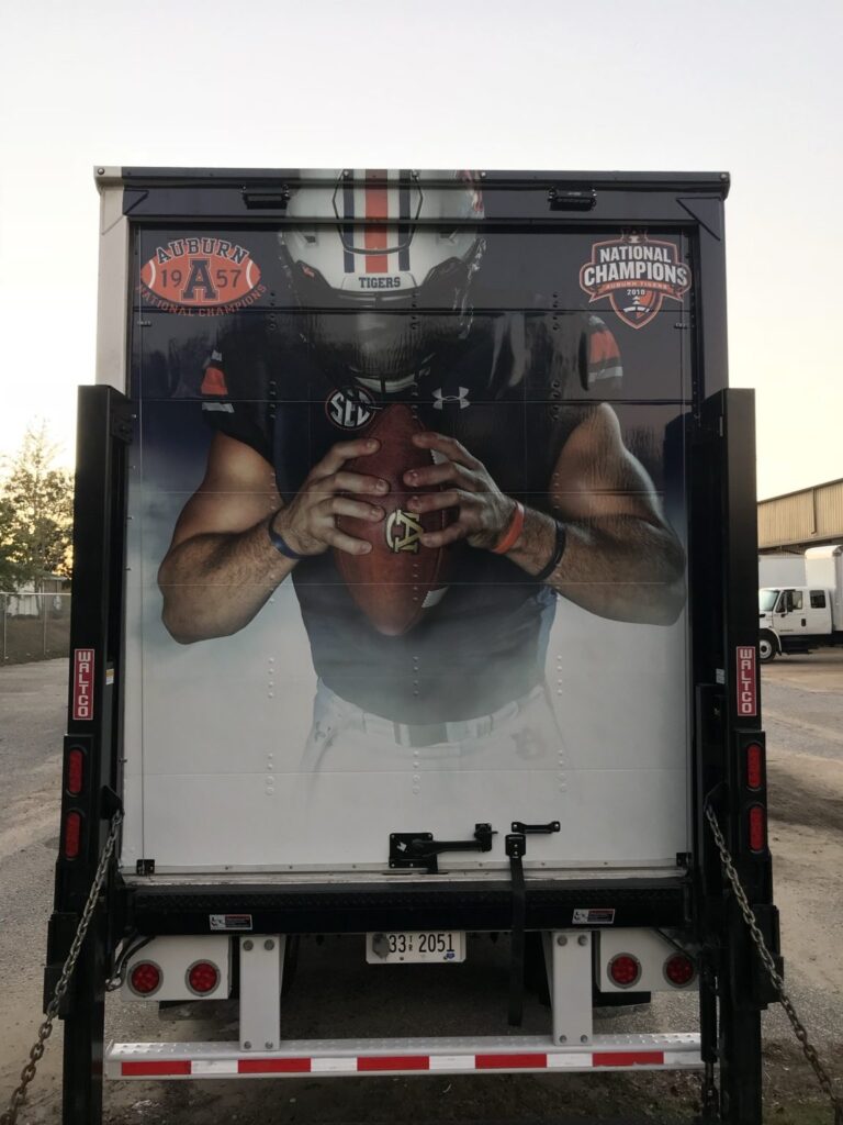 Auburn Football trailer rear roll-up door wrap featuring player imagery and national championship heritage logos