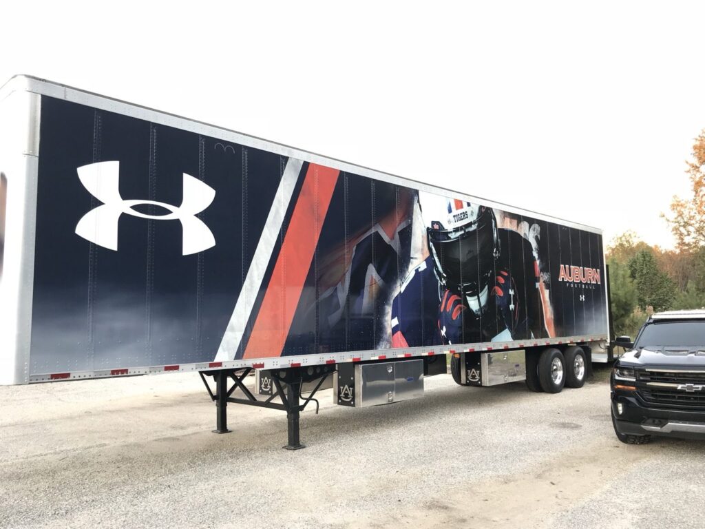 Angled view of Auburn University trailer wrap installation showing player graphics and Auburn Football branding across side panels