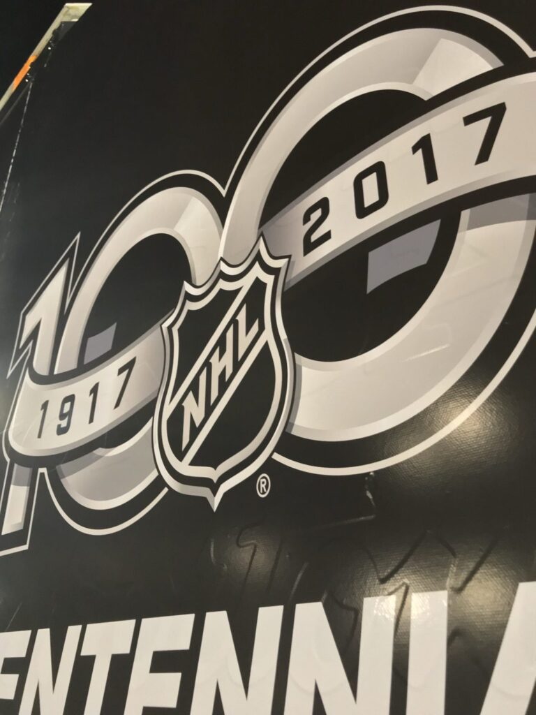 Close-up of NHL 100 Centennial anniversary emblem printed across black trailer graphics with visible exterior surface texture