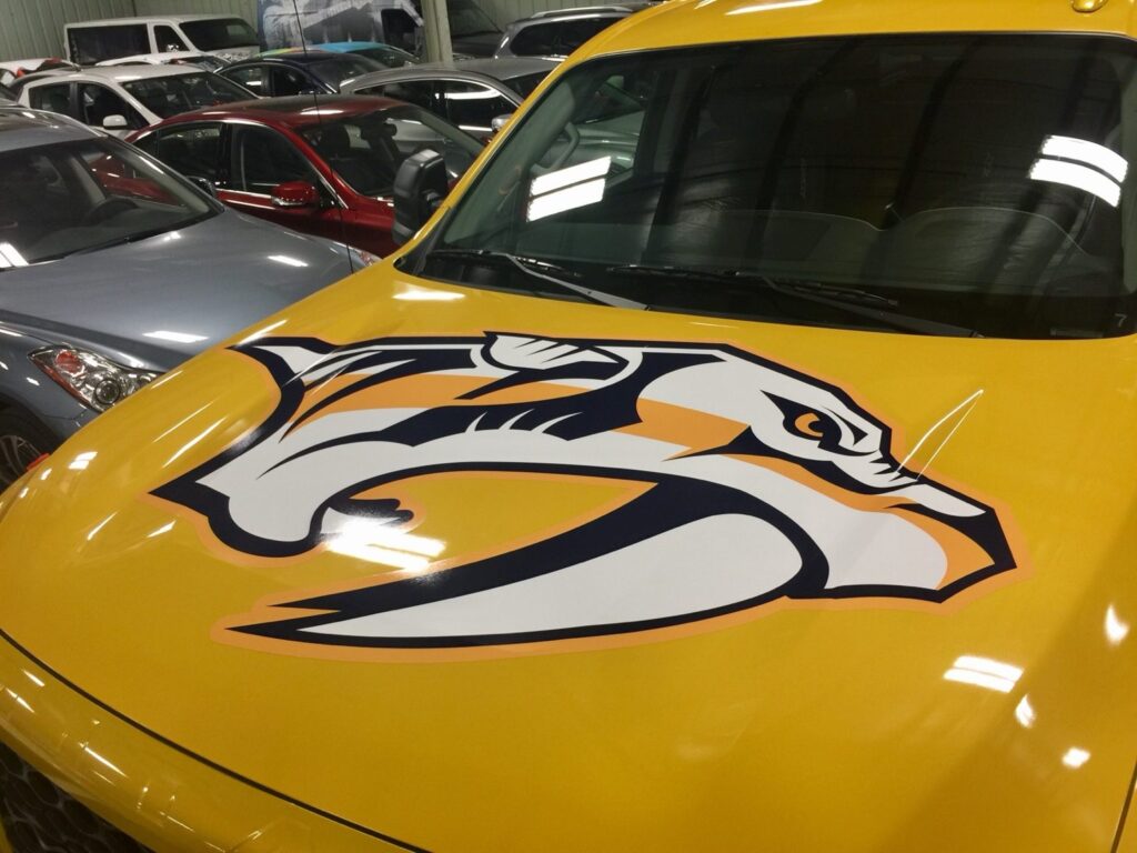 Oversized Nashville Predators saber-tooth tiger logo installed across the hood of a yellow Nissan Titan XD truck