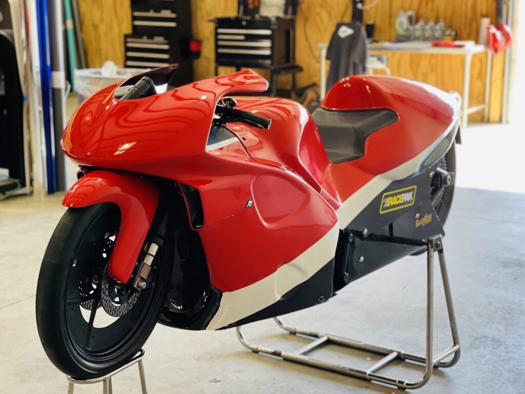 Front angled view of a racing motorcycle with red and white vinyl graphics