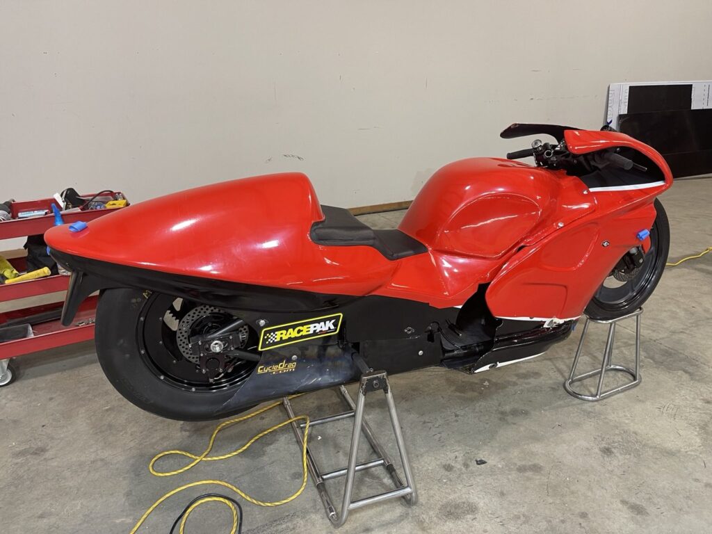 Red Pro Stock racing motorcycle inside the shop during the graphics project