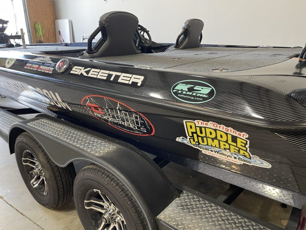 Close view of Skeeter boat graphics with carbon-fiber-style background and fishing-brand logos