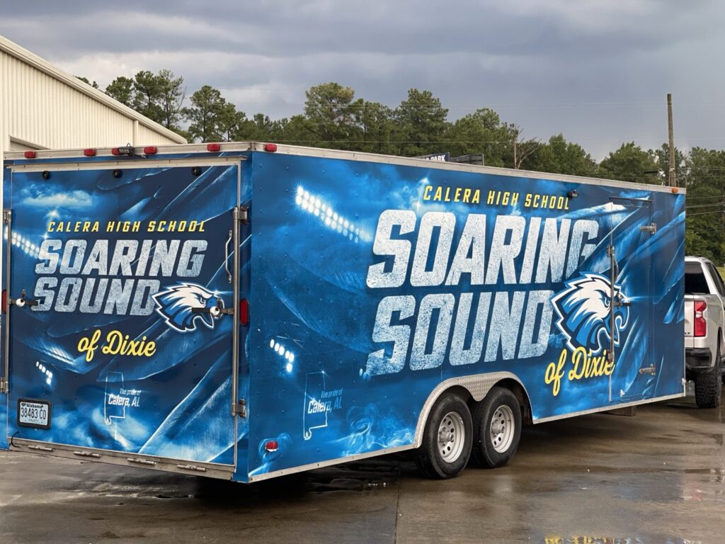 Blue enclosed dual-axle Calera High School marching band trailer showing Soaring Sound of Dixie lettering on the side and rear doors with a stylized eagle mascot.