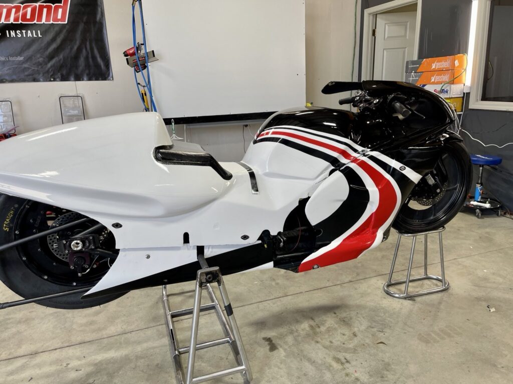 Three-quarter view of the drag bike with sweeping red, black and white graphics