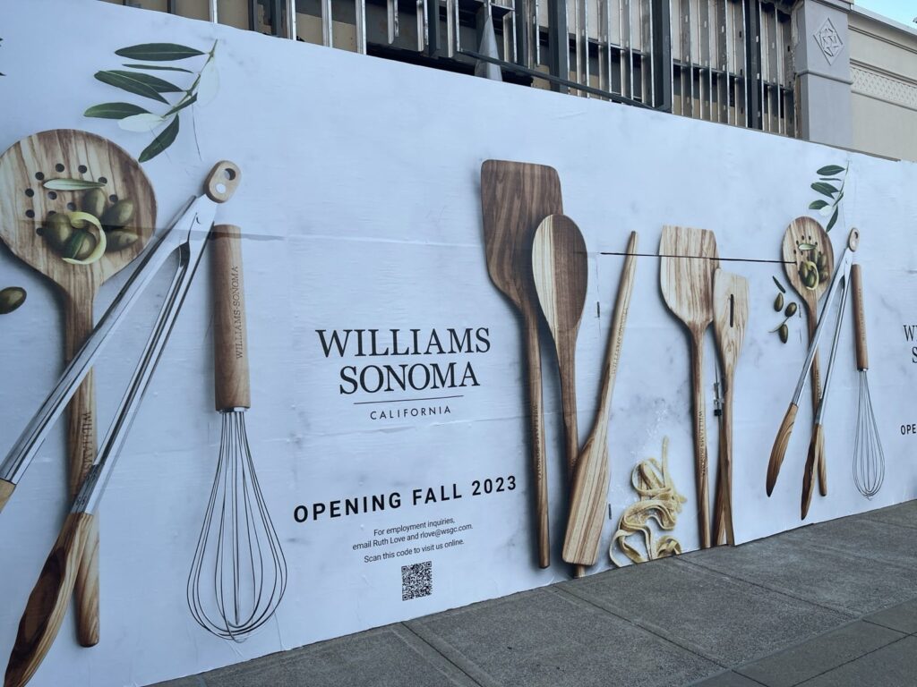 Williams Sonoma retail construction barricade graphics at The Summit in Birmingham, featuring kitchen utensils, the Williams Sonoma logo and Fall 2023 opening message.