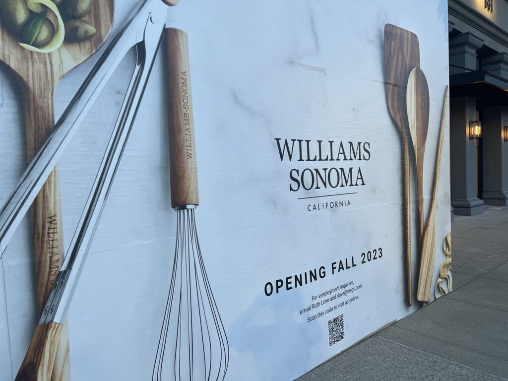 Close-up of Williams Sonoma retail construction wrap with whisk and wooden kitchen tools, Williams Sonoma California logo, Opening Fall 2023 lettering and a printed QR code.