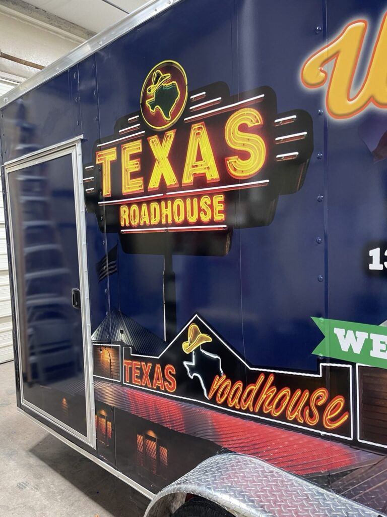 Close-up of the printed Texas Roadhouse sign logo and restaurant building imagery on the 3M IJ180 film covering the side of a trailer.