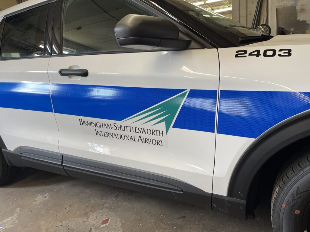Close-up of reflective blue 3M film and airport branding on a patrol SUV