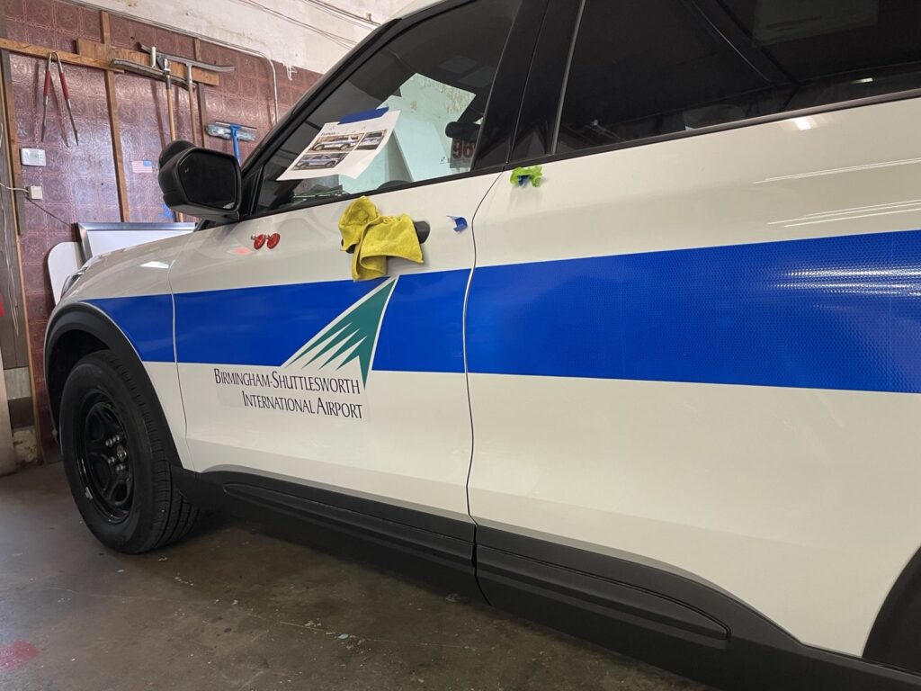 Airport patrol SUV with reflective blue stripe and facility logo being installed