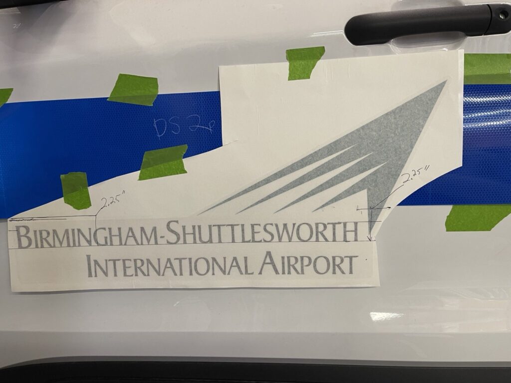 Alignment template over reflective blue film on an airport patrol vehicle during installation