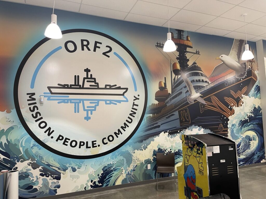 Completed ORF2 maritime wall mural with a ship, ocean waves and the facility emblem