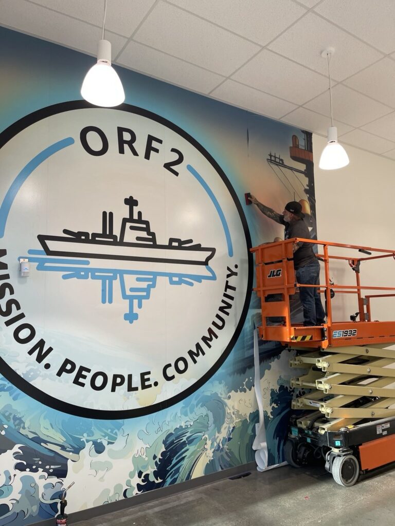 Black Diamond Designs installer applying large-format ORF2 wall graphics from a scissor lift