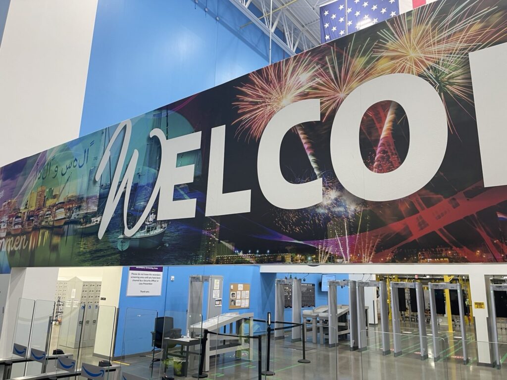 Oversized welcome graphics installed above entry security turnstiles