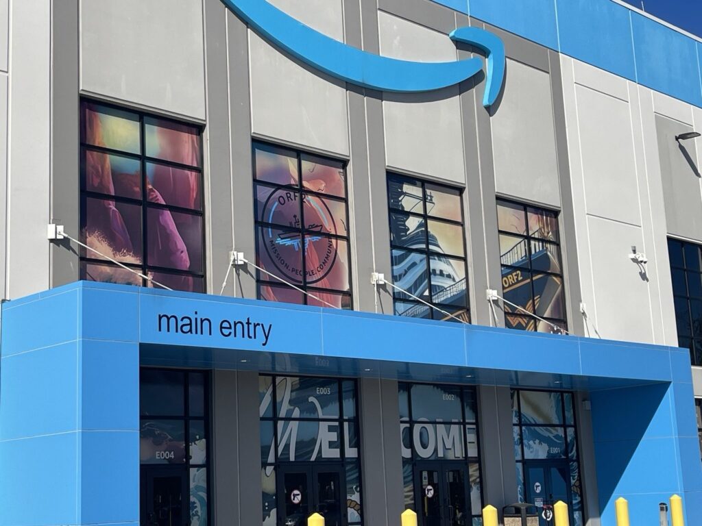 Exterior Amazon facility with colorful upper-story window graphics over the main entry