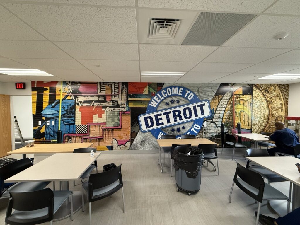 Wide interior view of break room seating in front of a floor-to-ceiling colorful Welcome to Detroit printed wall wrap.