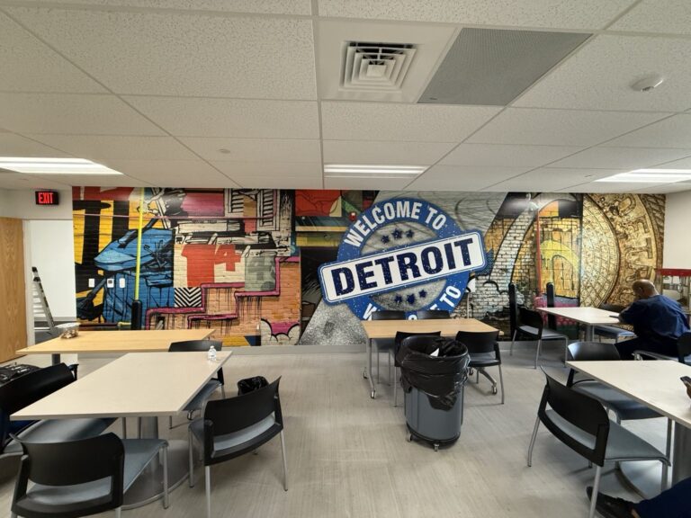 Wide interior view of break room seating in front of a floor-to-ceiling colorful Welcome to Detroit printed wall wrap.