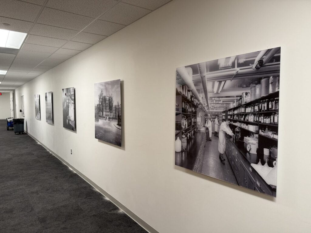 Long carpeted hallway at Henry Ford medical building in Detroit with mounted black-and-white historical photo panels along a white wall.