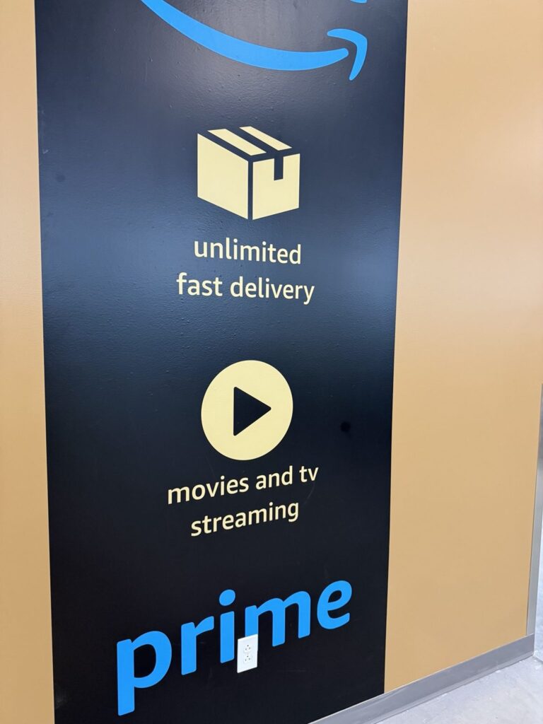 Close-up of Amazon Prime branded wall panel showing a package delivery icon, video play symbol, and blue Prime wordmark.