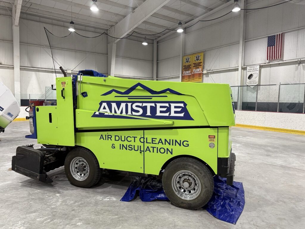 Full side view of Amistee ice resurfacer with navy mountain logo and air duct cleaning and insulation wording