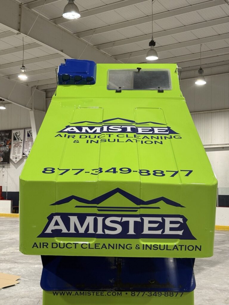 Rear view of lime-green Amistee Zamboni with large company logo, service lettering and phone number in a Flint ice arena