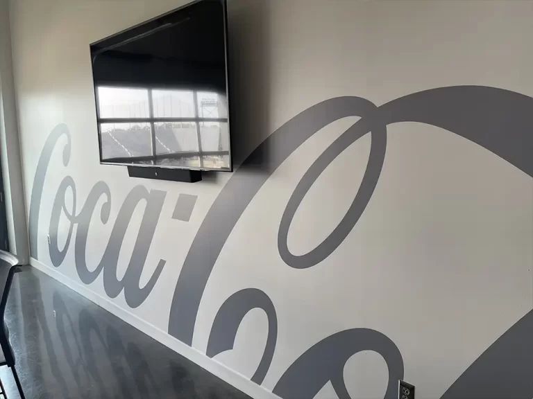 Gray Coca-Cola script wall graphic behind a mounted television