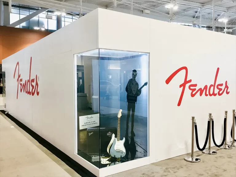Fender logos on white exhibition walls beside a guitar display