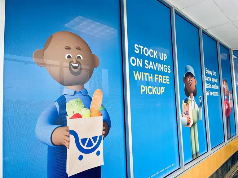 Blue grocery pickup promotional graphics across storefront windows