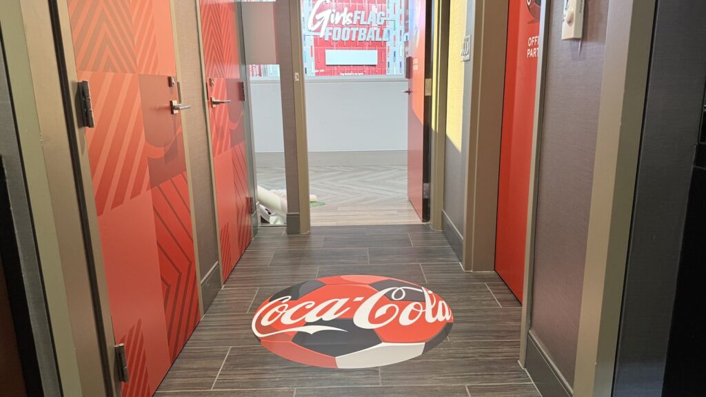Coca-Cola soccer ball floor graphic and red patterned door graphics in a Mercedes-Benz Stadium suite hallway.
