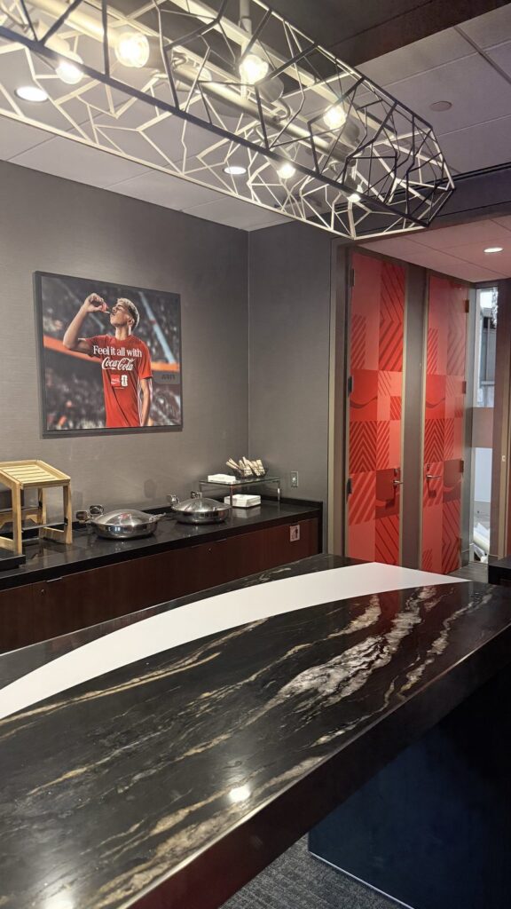 Mercedes-Benz Stadium suite buffet with a Coca-Cola ribbon graphic on the table top and red patterned door graphics.
