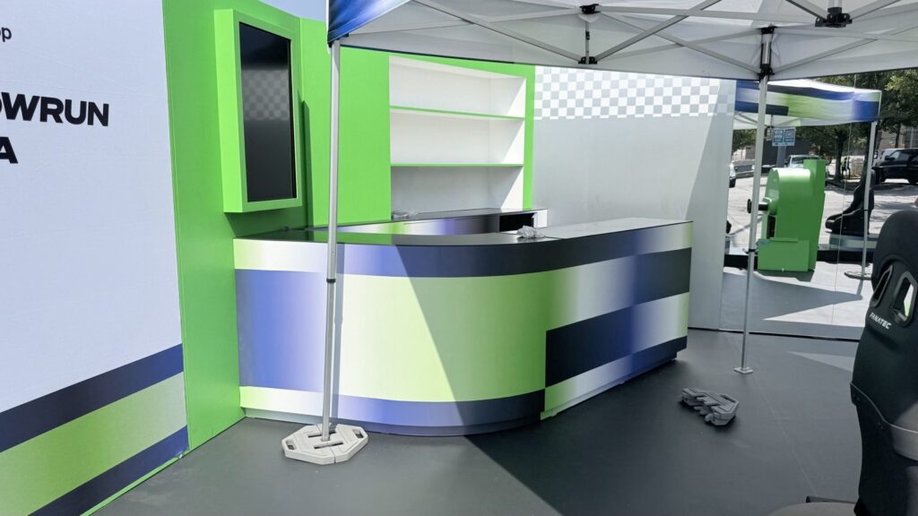 Graphics applied to a curved activation counter in front of a sponsor backdrop