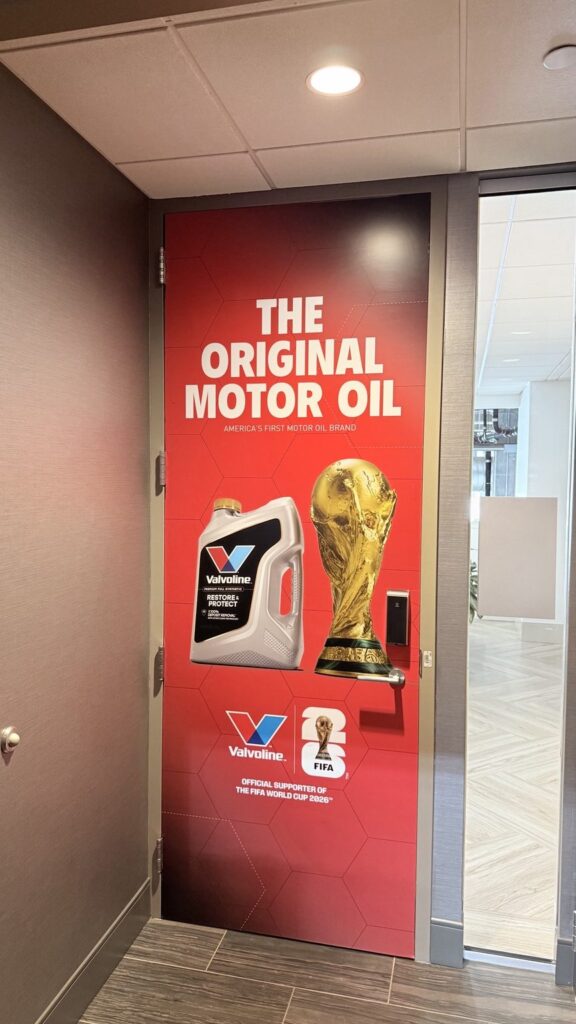 Valvoline door graphic with product and trophy imagery beside an open suite doorway
