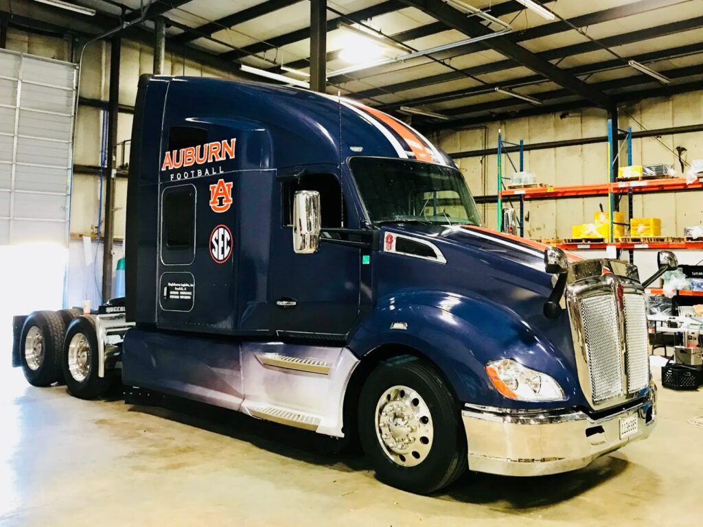 Auburn Tigers semi-truck with orange-and-white accent stripes and Auburn Football graphics